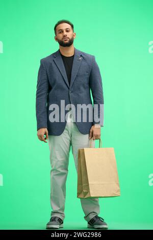 Ein Mann in voller Länge, auf grünem Hintergrund, mit Taschen Stockfoto