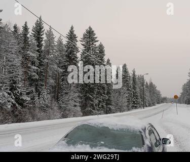 Eine vereiste und schneebedeckte Straße in Paltamo, Finnland im Winter. Die Straßenbedingungen sehen eisig und gefährlich aus. Stockfoto