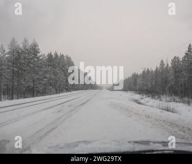 Eine vereiste und schneebedeckte Straße in Paltamo, Finnland im Winter. Die Straßenbedingungen sehen eisig und gefährlich aus. Stockfoto