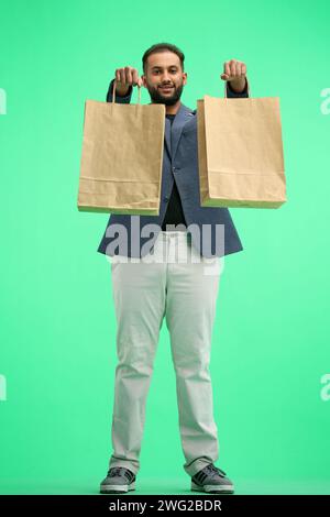 Ein Mann in voller Länge, auf grünem Hintergrund, mit Taschen Stockfoto