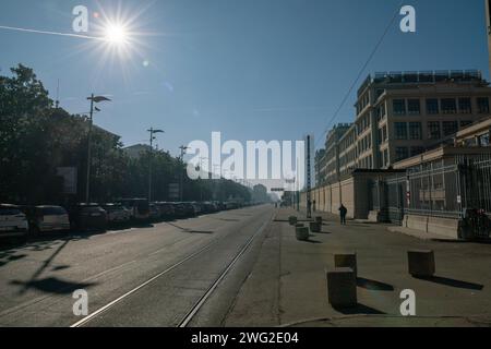 Stadtstraße mit wenig Verkehr, die Stadt ist morgens schläfrig. Leere U-Bahn mit Sonne und klarer Himmelperspektive auf eine gerade Straße. Wenige Autos. Stockfoto