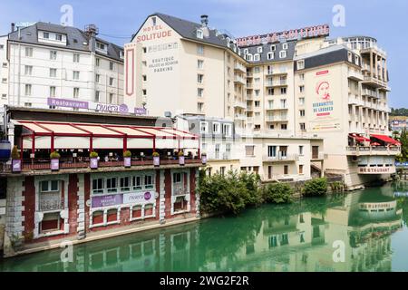 Der Fluss Ousse, Häuser, Restaurants und Hotels und ihre Reflexion im Wasser. Blick von der Brücke Pont Vieux. Lourdes, Frankreich. Stockfoto