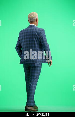 Ein Mann in voller Höhe, auf grünem Hintergrund, läuft Stockfoto