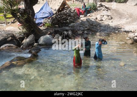 Eine lebendige Flussszene in Sarkegad, einem ländlichen nepalesischen Bergdorf in Humla. Nepalesische Frauen in traditioneller Kleidung waschen sich im Fluss. Stockfoto