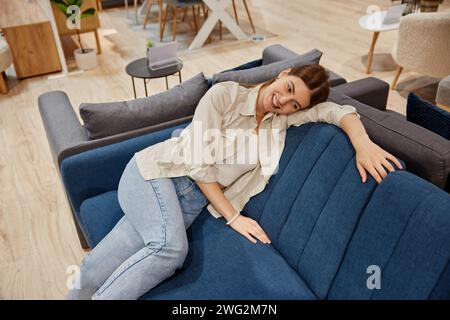 Eine junge Frau, die im Möbelgeschäft nach einer neuen Couch sucht Stockfoto
