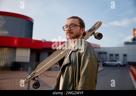 Porträt eines gutaussehenden lässigen Mannes mit Skateboard über Downtown Hintergrund Stockfoto