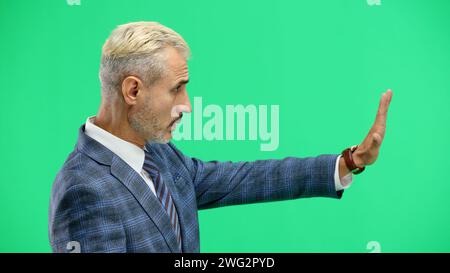 Ein Mann aus der Nähe, auf grünem Hintergrund, zeigt ein Stoppschild Stockfoto