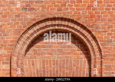 Wandstruktur mit Geometrie mit rotem Ziegelstein, Ziegelwand mit rotem Rahmen Backsteinbogen Stockfoto