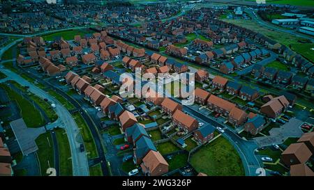 Aus der Vogelperspektive auf ein Vorstadtviertel in der Abenddämmerung mit Häuserreihen und verwinkelten Straßen. Stockfoto