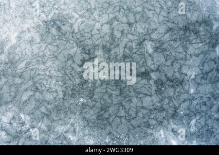 Textur eines gefrorenen Sees mit vielen Rissen auf der Eisoberfläche. Draufsicht. Stockfoto
