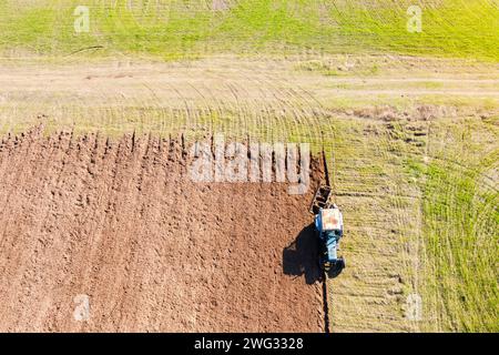 Draufsicht des Pflügens des Traktors auf dem landwirtschaftlichen Feld. Agrarbetriebskonzept. Boden für die neue Ernte vorbereiten. Stockfoto