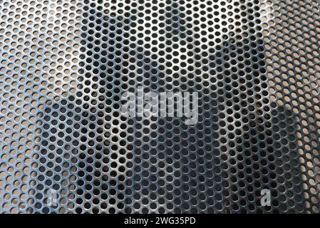 Metallgitter, Hintergrund, mit runden identischen Löchern, Metallstruktur mit Schatten und Licht. Stockfoto