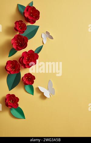 Blick von oben auf einige rote Blumen, die in einer Linie mit weißen Schmetterlingen auf gelbem Hintergrund angeordnet sind. Vektor Papier Kunst Blumen Set. 3D Origami Blumen Stockfoto
