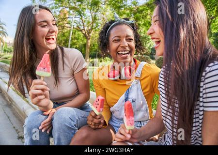 Eine Gruppe junger, multirassischer Freundinnen lachend und genießt Eis im Park am Sommertag. Stockfoto