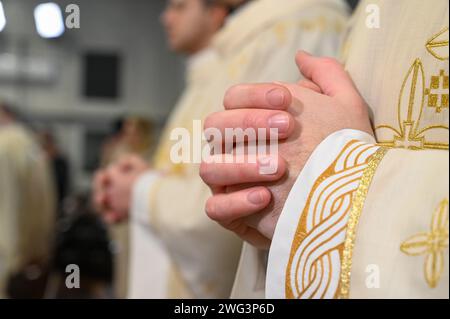 Katholische Priester in liturgischen Gewändern beten mit gefalteten Händen. Hände eines christlichen Mannes, der in der Kathedrale betet. Mitternachtsmesse in der Kirche. Stockfoto