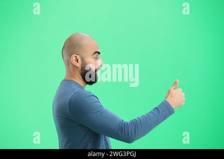 Ein Mann, auf grünem Hintergrund, in Nahaufnahme, zeigt einen Daumen nach oben Stockfoto