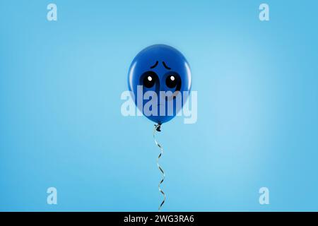 Blauer Ballon mit trauriger Fläche auf hellblauem Hintergrund Stockfoto