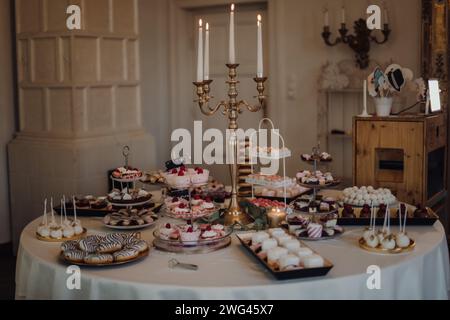 Ein Tisch mit verschiedenen Desserts und einer beleuchteten Kerze. Stockfoto