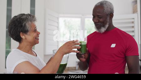 Birassische Frau und afroamerikanischer Mann teilen sich zu Hause ein gesundes Getränk Stockfoto