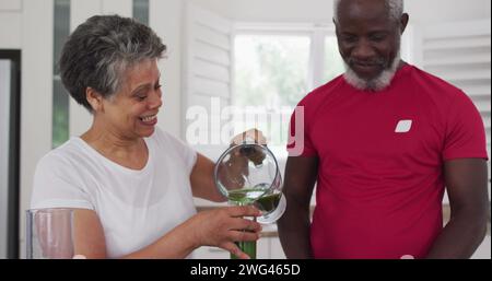 Eine birassische Frau schenkt einem Afroamerikaner zu Hause einen Drink Stockfoto