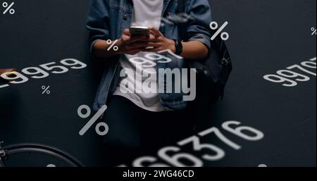 Mehrere sich ändernde Zahlen und Prozentsymbole, die mit dem Smartphone im mittleren Bereich des Mannes schweben Stockfoto