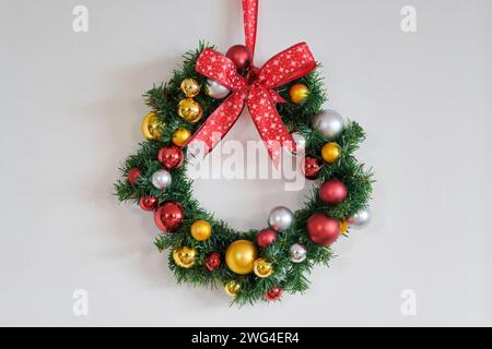 Weihnachtskranz mit rotem Band mit Sternen und Dekoration mit goldenen, roten und silbernen weihnachtskugeln. Stockfoto