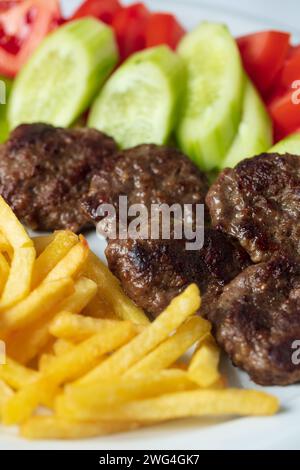 Traditionelle türkische Fleischbällchen serviert mit Pommes frites Tomaten Stockfoto