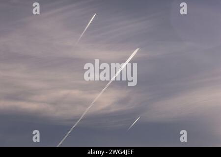 Hoch fliegende Passagierflugzeuge lassen Kondensstreifen im Gefolge. Die extrem kalte, trockene Luft in großer Höhe hinterlässt Eiskristalle aus den Motoren Stockfoto