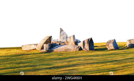 Zusammensetzung von Steinblöcken auf einem Rasen, der von der untergehenden Sonne beleuchtet wird, mit langen Schatten, die vom Hintergrund isoliert sind. Stockfoto