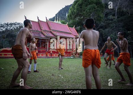 Einheimische und burmesische Mönche spielen am späten Nachmittag im Wat Tham Pla Tempel Fußball. Wat Tham Pla (Höhlenfischtempel) wird auch als „Affentempel“ für thailändische Einheimische bezeichnet und liegt 16 Kilometer von Mae Sai, der nördlichsten Stadt Thailands, entfernt. Stockfoto