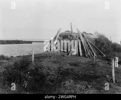 Am Selawik River, 1929. Blockhütte mit Tür am Ufer des Selawik River; draußen ist ein Hund an einen Pfosten gekettet. Stockfoto