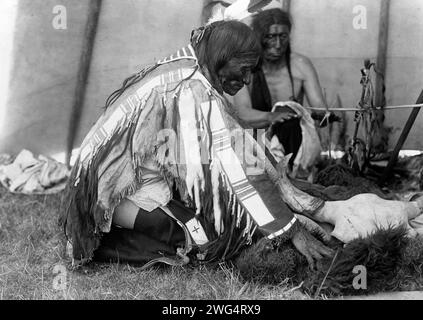 HU Kalowa Pi-entfernt die Abdeckung, c1907. Das Innere des Tipis, ein Mann, der auf dem Boden kniet und Büffelverstecke um den Schädel auf dem Boden, ein weiterer Mann hinter dem Altar wärmt die Hände durch Feuer. Stockfoto