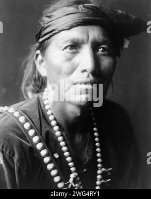 Der weiße Sänger, 1906. Kopf-und-Schultern-Porträt des Navajo-Mannes, leicht nach rechts gerichtet, mit Stirnband und silberner Kürbisblütenkette. Stockfoto