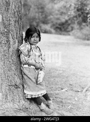 Innocence, ein Umatilla-Mädchen, ein Porträt in voller Länge, stehend am Baum, etwas nach rechts gerichtet, c1910. Stockfoto