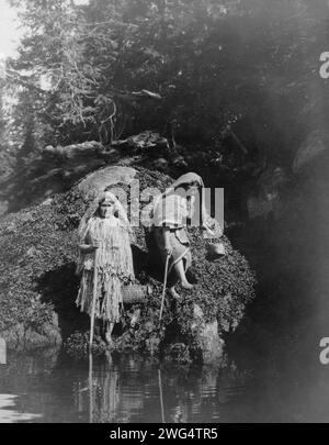 Sammeln von Algen-Clayoquot, 1910. Zwei Clayoquot-Indianer mit Körben am Wasser. Stockfoto