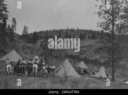 Autorenlager unter den Spokan, 1910. Fünf Zelte auf einer Rodung, Edward S. Curtis in der Mitte, Spokane Männer und Frauen auf dem Pferd links. Stockfoto