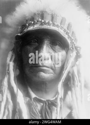 Red Hawk (Che-tan Luta)-Oglala, um 1907. Red Hawk, Oglala Sioux Indianer, Kopf-und-Schultern-Porträt, nach vorne gerichtet, mit Federkopfschmuck. Stockfoto