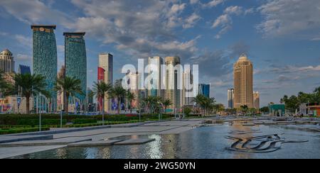 Skyline von Doha in der westlichen Bucht Doha, Katar Nachmittagsaufnahme aus dem Hotelpark mit künstlichem See im Vordergrund und Wolken im Himmel im Hintergrund Stockfoto