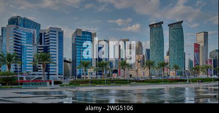 Skyline von Doha in der westlichen Bucht Doha, Katar Nachmittagsaufnahme aus dem Hotelpark mit künstlichem See im Vordergrund und Wolken im Himmel im Hintergrund Stockfoto