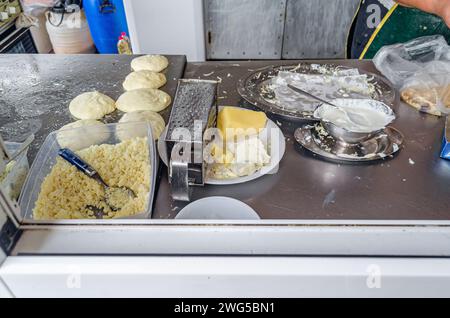 Straßenverkäuferstand, der langos mit geriebenem Käse und Sauerrahm zubereitet; langos ist ein typisch ungarisches Essen, das aus einem frittierten Fl besteht Stockfoto