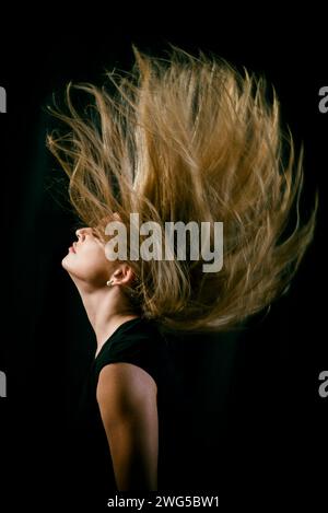 Seitenansicht einer schönen jungen Frau, die die Haare hochwirft Stockfoto