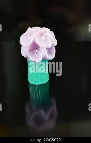 Wunderschöner Blumenstrauß aus violetter Seife, sehr originell und wunderschön. Handgefertigte Seife auf einer schwarzen glänzenden Oberfläche. Stockfoto