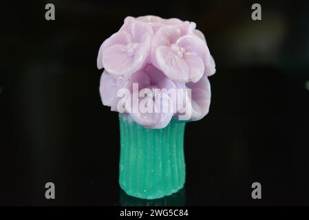 Wunderschöner Blumenstrauß aus violetter Seife, sehr originell und wunderschön. Handgefertigte Seife auf einer schwarzen glänzenden Oberfläche. Stockfoto