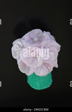 Wunderschöner Blumenstrauß aus violetter Seife, sehr originell und wunderschön. Handgefertigte Seife auf einer schwarzen glänzenden Oberfläche. Stockfoto