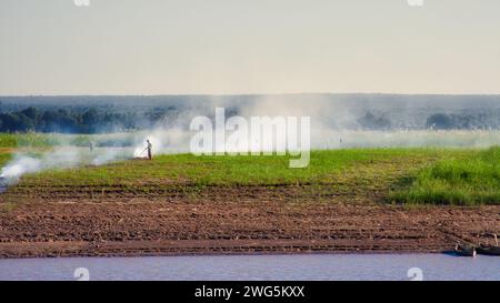 Ein Mann, der ein Feld mit viel Rauch abbrennt Stockfoto