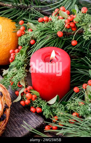 Rote Weihnachtskerze mit Moos und rote Beeren (Zwergmispel Horizontalis) Kranz geschmückt. Stockfoto