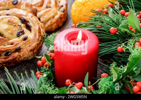 Rote Weihnachtskerze mit Moos und rote Beeren (Zwergmispel Horizontalis) Kranz geschmückt. Stockfoto