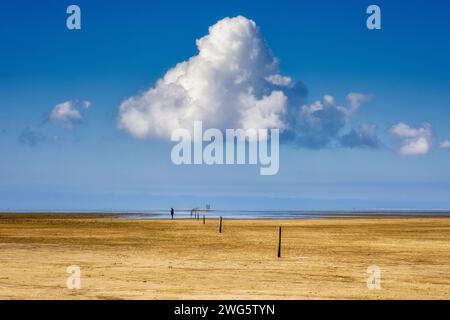 Ein einsamer Mann steht am Strand in der Sonne über ihm eine große Wolke Stockfoto