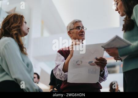 Leitender Geschäftsmann diskutiert Diagramme während einer Teambesprechung Stockfoto