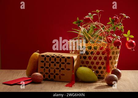 Viele Obstsorten auf einem Holztisch mit roten Umschlägen und einigen Granatäpfeln auf einem Korb. Vorderansicht. Chinesisches Urlaubsmodell Stockfoto